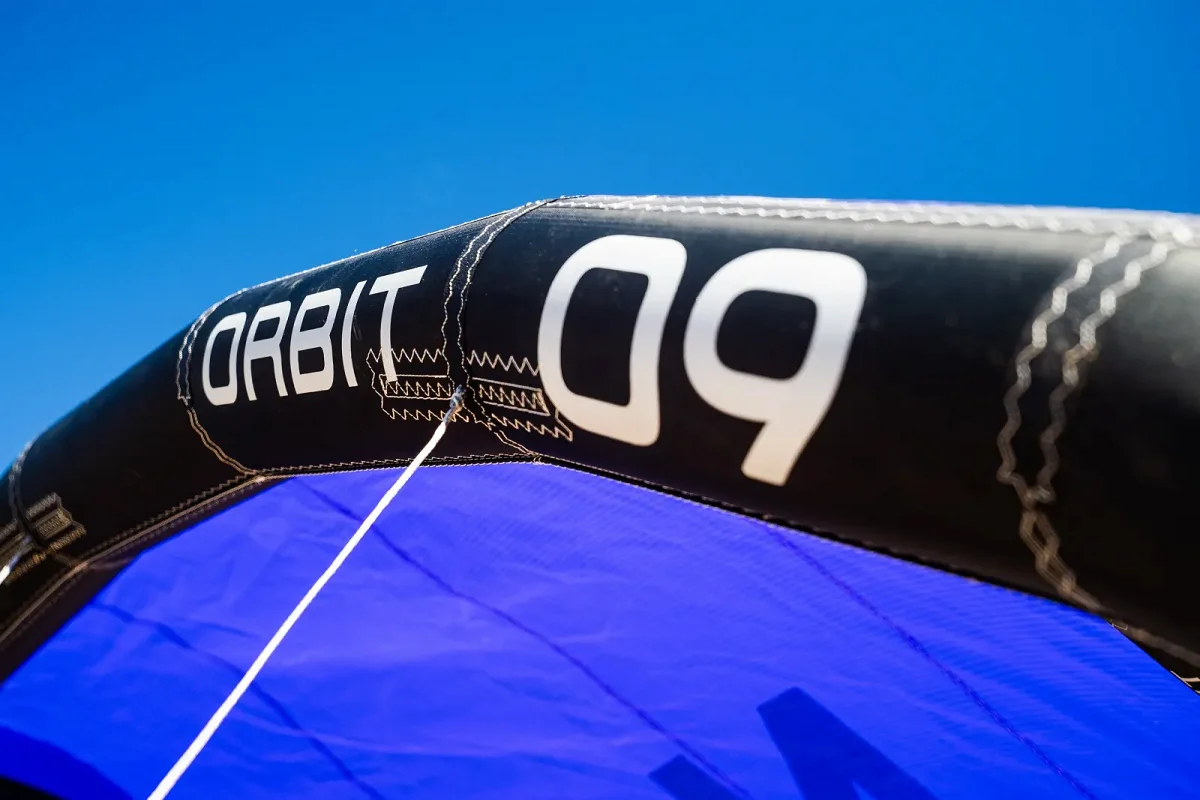 Gros plan sur le bord d'attaque noir d'une aile North Orbit 09, une bride blanche tendue devant la toile bleue