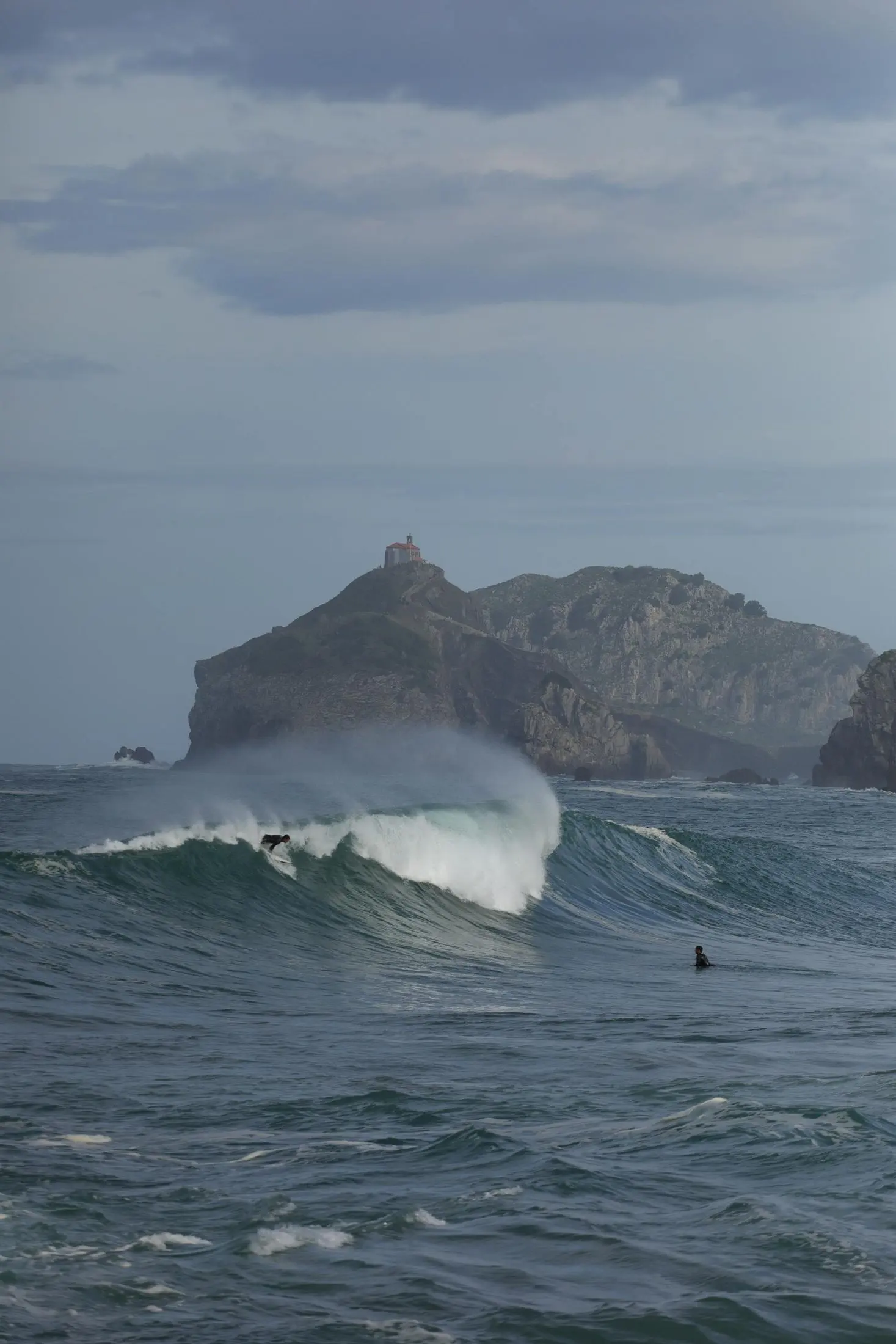 Surfeurs sur les vagues près de Gaztelugatxe, Pays Basque
