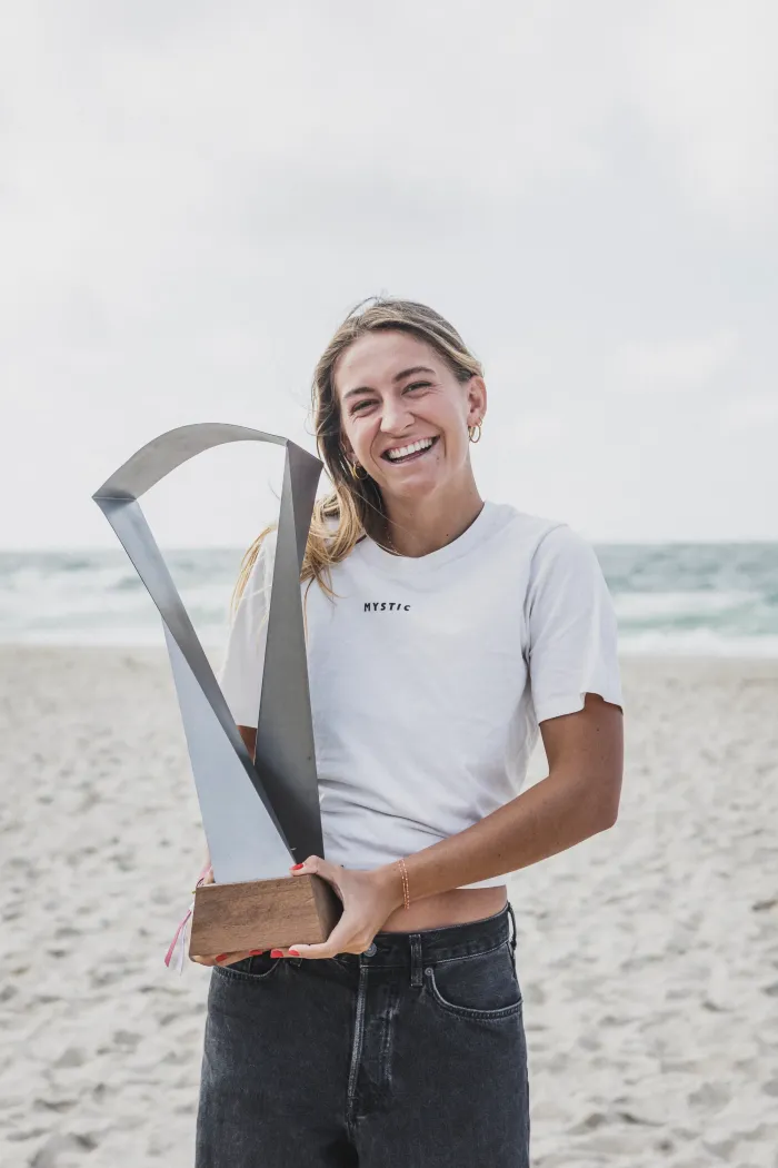 Capucine Delannoy, en t-shirt blanc sur la plage de Sylt, tenant devant elle le trophée métallique de championne du monde 2026