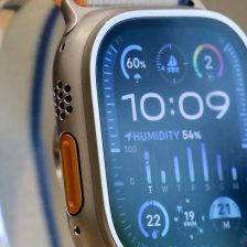Gros plan sur une Apple Watch Ultra 2 en titane, bouton Action orange sur la tranche, cadran affichant l'humidité, la vitesse du vent et un indicateur de navigation