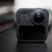 Gros plan de face sur une caméra 360 GoPro posée sur une table sombre, objectif hémisphérique bombé au centre du boîtier